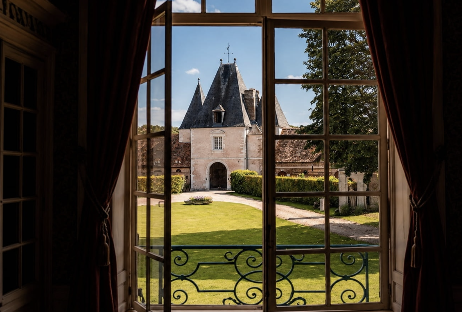 A Normandy château seen through an open window with curtains